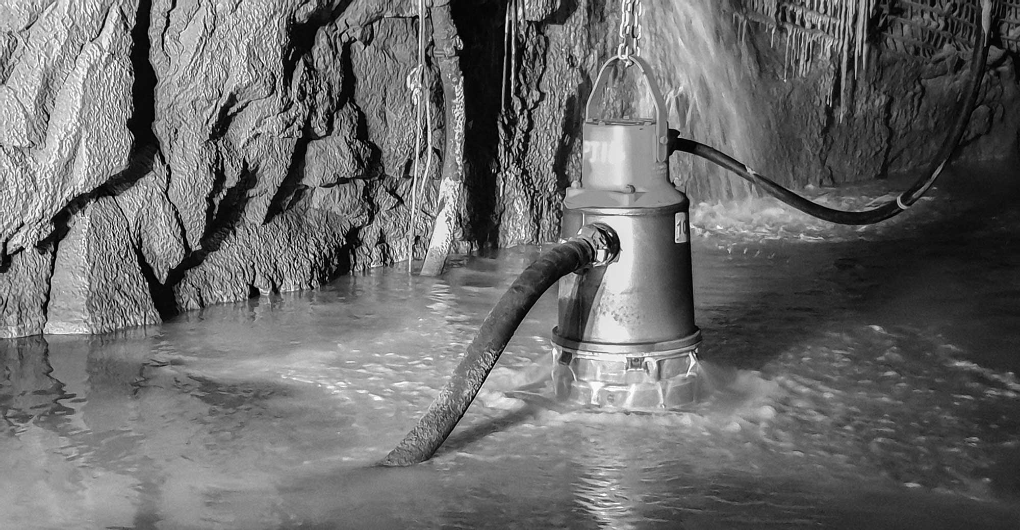 An underground mine dewatering pump pumping water while semi-submersed in an underground mine