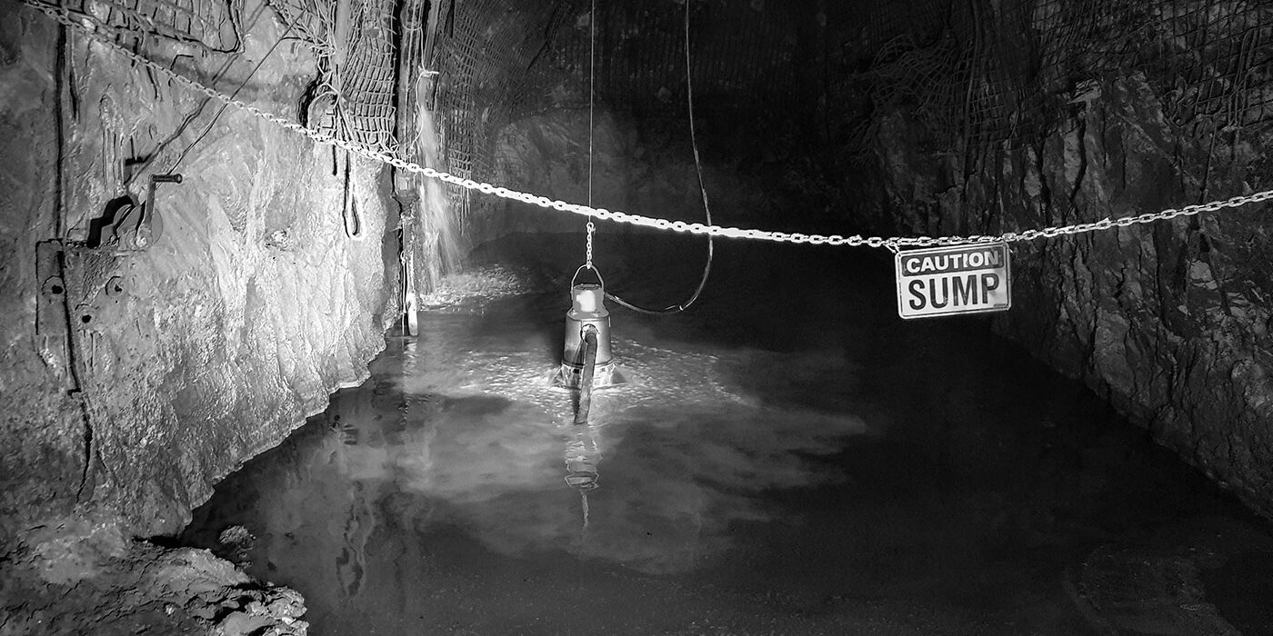 An underground mine dewatering pump pumping water while submersed in an underground mine